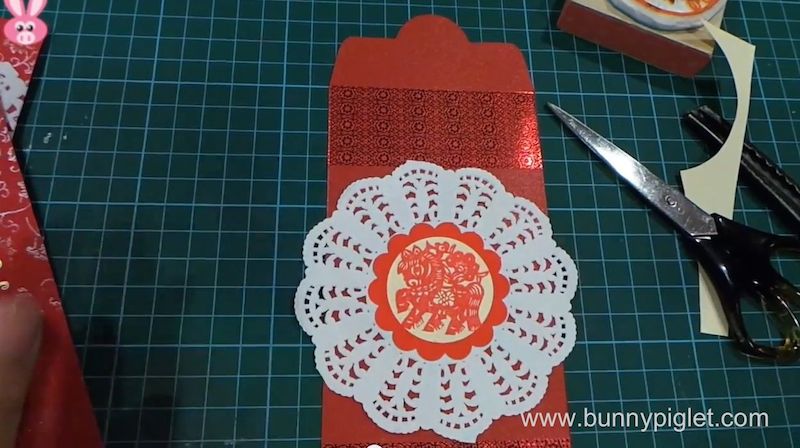 stick paper doily onto red packet 